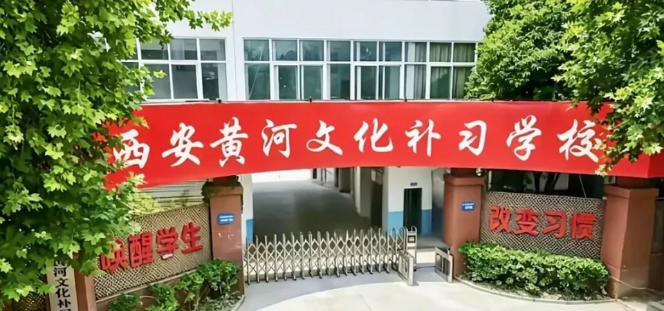 西安黄河文化补习学校校门实拍，红色横幅上写着校名，两侧砖砌门柱挂着「唤醒学生」「改变习惯」字样的镂空牌匾，中间是不锈钢伸缩门